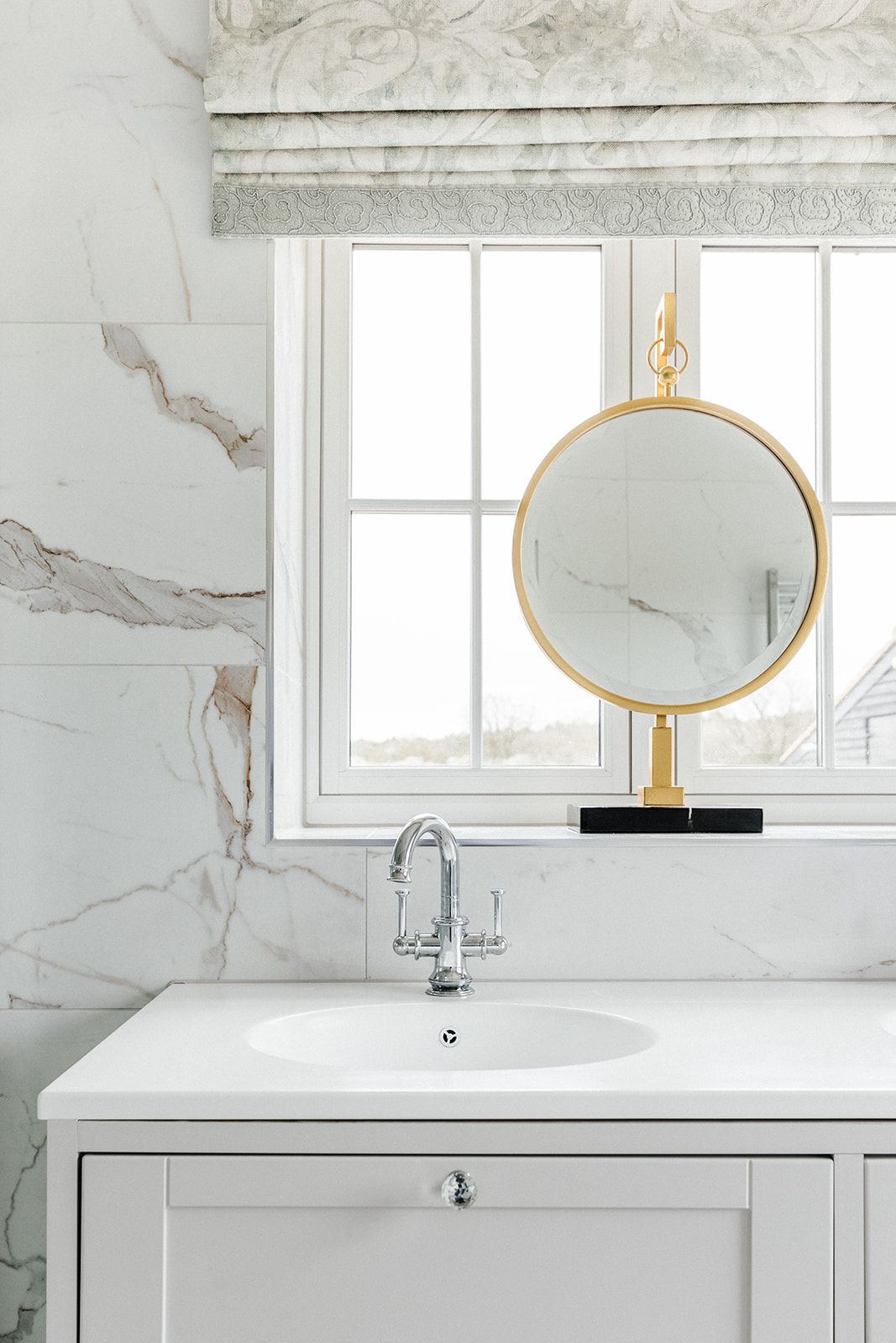 Marble bathroom detail with gold vanity mirror and chrome taps